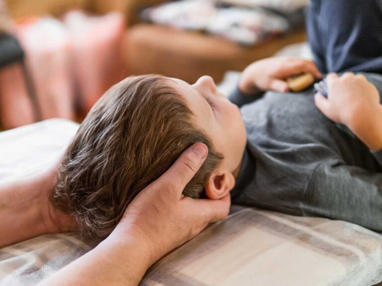 Adult gently stretching beside a chair in a bright home while holding a warm compress for joint comfort.